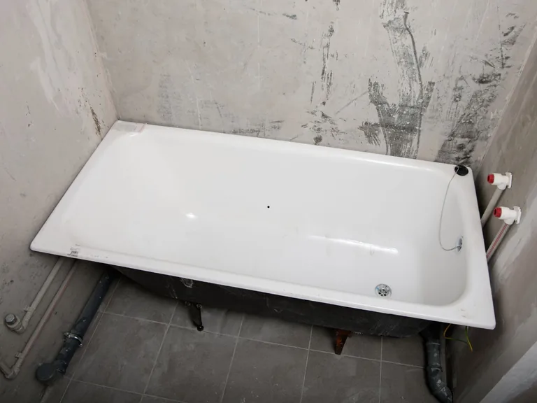 Bathtub and exposed plumbing lines during a bathroom installation