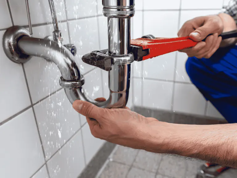 Emergency plumbing repair on a leaking sink drain pipe