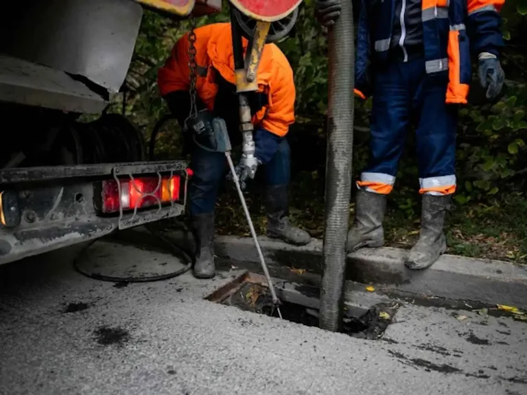 Professional crew completing sewer repair work at an access opening