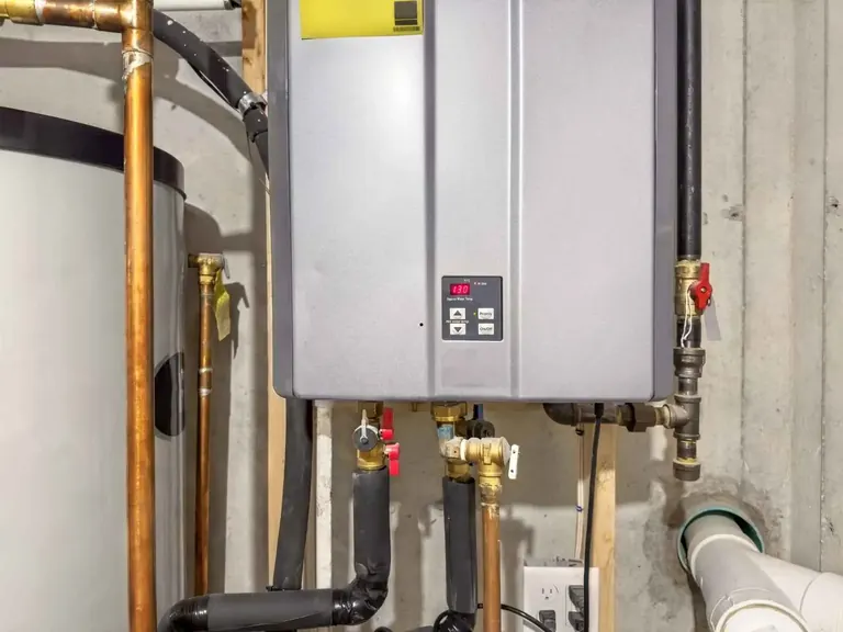 Tankless water heater connected in a mechanical room with visible service valves and piping