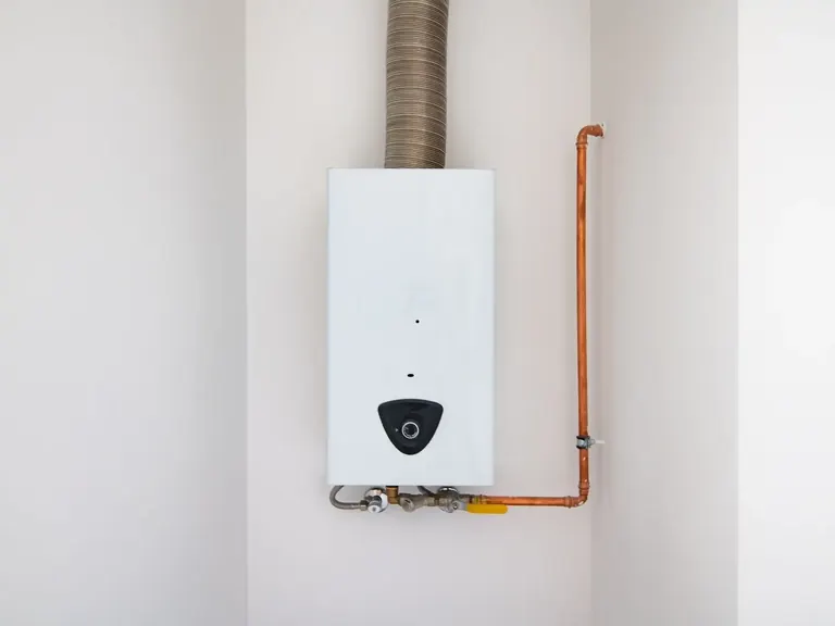 Wall-mounted tankless water heater connected to copper piping