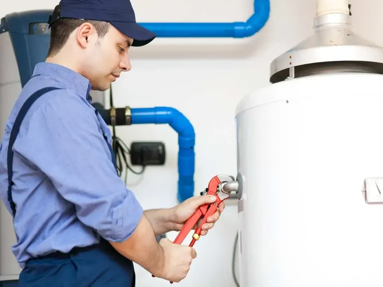 Plumber tightening a water heater connection during installation service