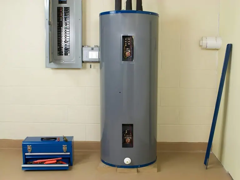 Electric tank water heater opened for diagnostic repair beside a service toolbox